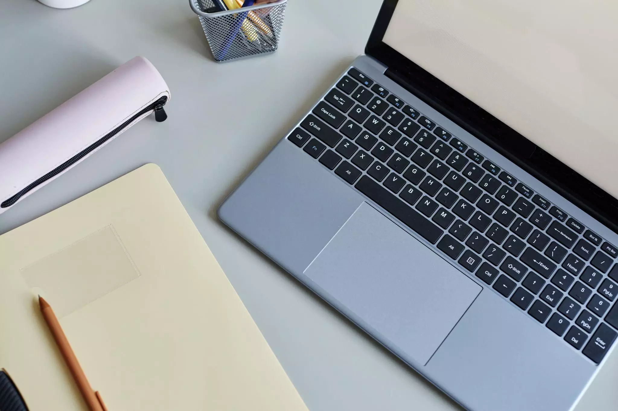 Content Workspace with Laptop and Notebook Laptop, notebook, and pencil case arranged on a desk workspace